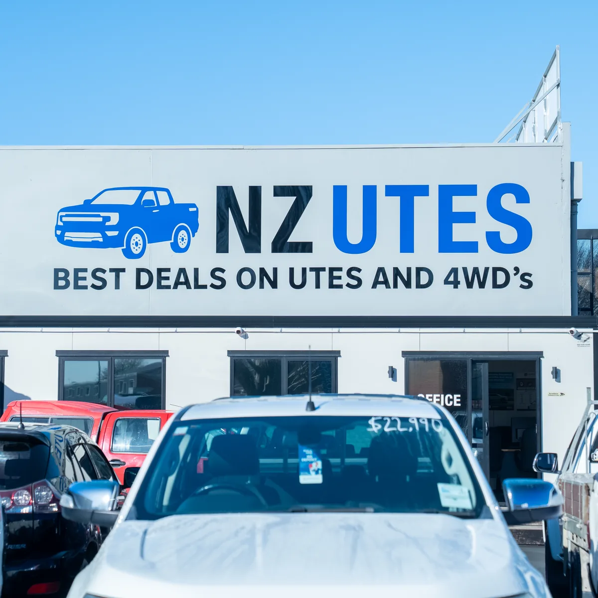 The NZ Utes yard frontage, signage above a row of utes for sale